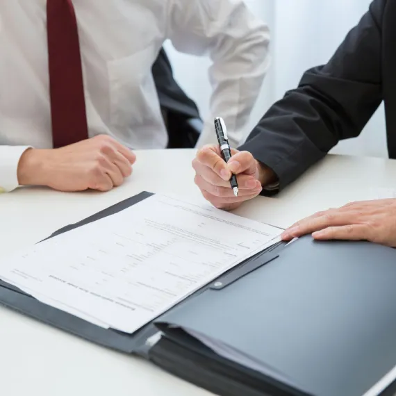 Two advisors review and sign a document at a meeting table